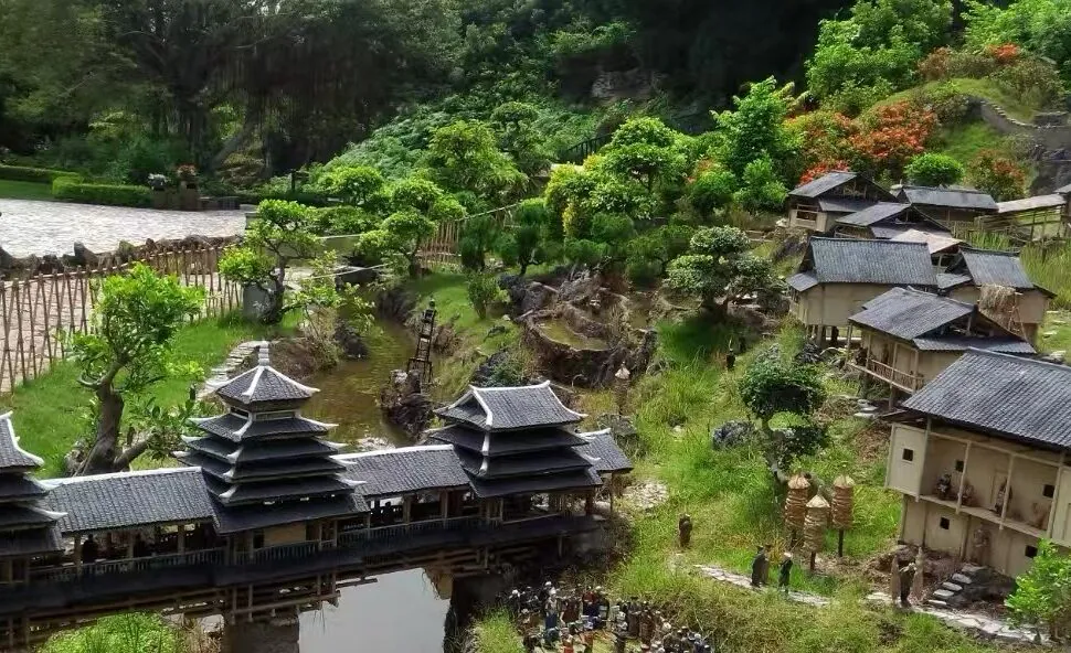 Splendid China Folk Village,Shenzhen,Chinatour Miniature traditional Asian village with tiered pagoda buildings, a wooden bridge, and lush garden scenery.