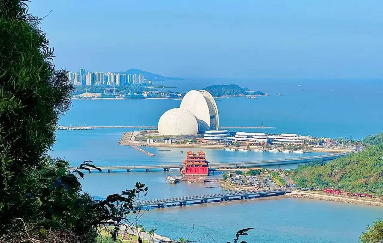 Zhuhai Lovers’ Road Seaside,Zhuhai,Chinatour Coastal panorama with white futuristic domes on a peninsula, a red pagoda and a bridge over blue water.