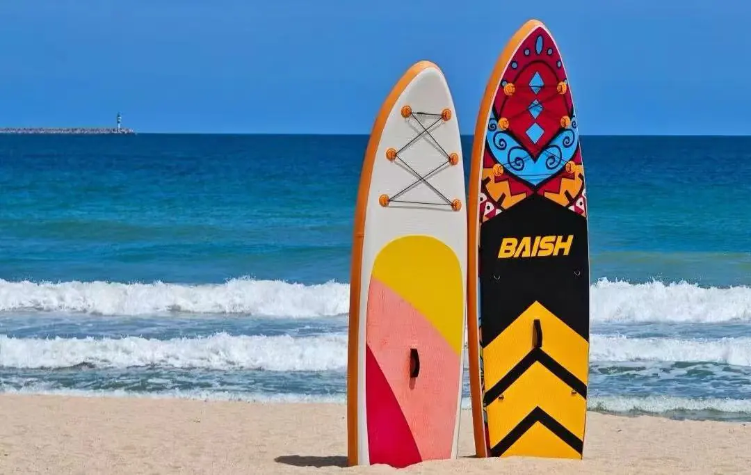 Dadonghai Beach,Sanya,Chinatour Two colorful surfboards upright in the sand at the beach with blue ocean and waves behind them.