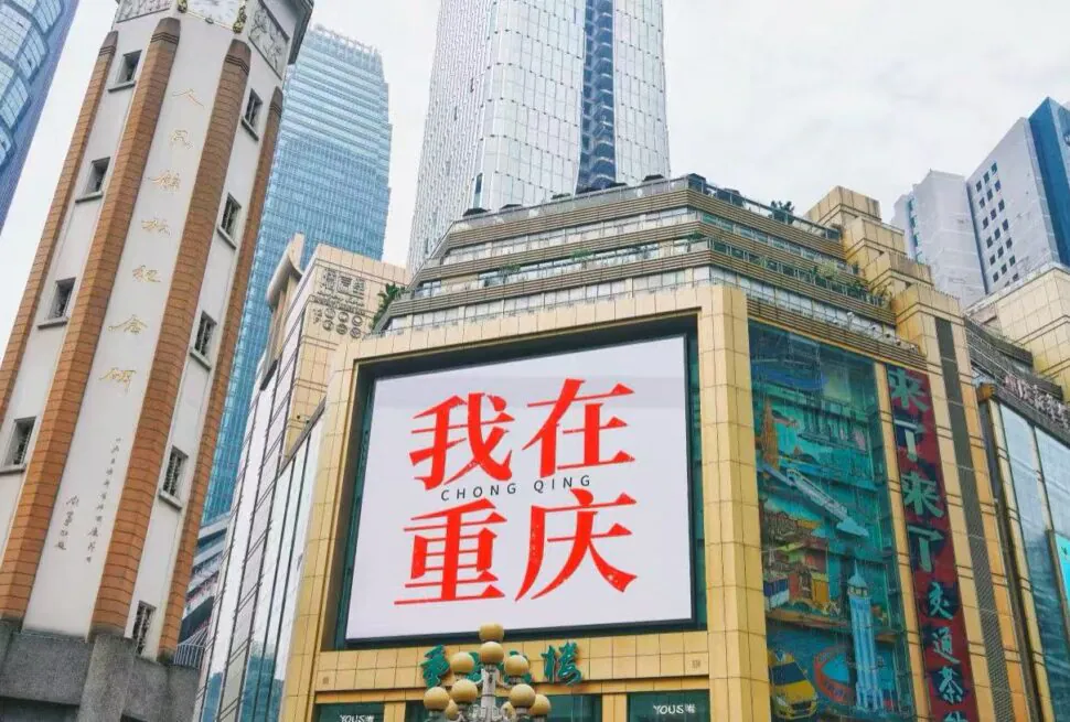 Jiefangbei Pedestrian Street,Chongqing,Chinatour Large billboard on a gold-framed building in Chongqing displaying red Chinese text '我在重庆' (I'm in Chongqing).
