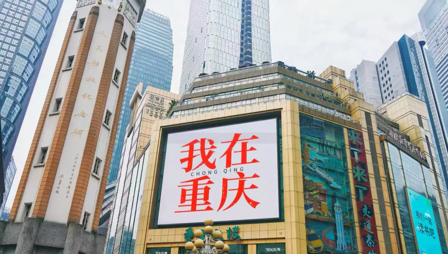 Jiefangbei Pedestrian Street,Chongqing,Chinatour Large billboard on a gold-framed building in Chongqing displaying red Chinese text '我在重庆' (I'm in Chongqing).