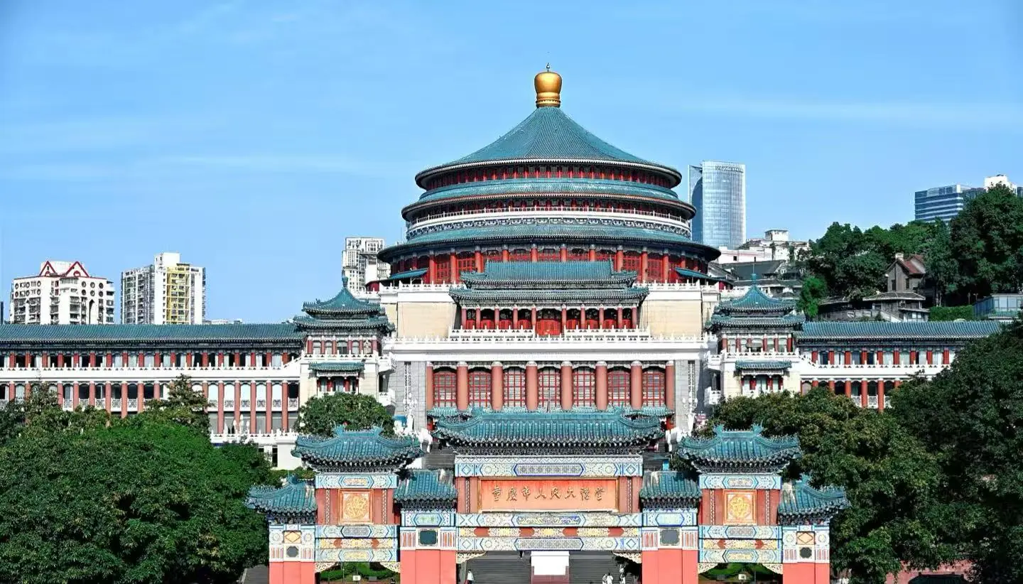 People’s Assembly Hall,Chongqing,Chinatour Large Chinese temple complex with a circular, multi-tiered roofed hall and ornate gate in the foreground, flanked by red columns and turquoise tiles against a city skyline.
