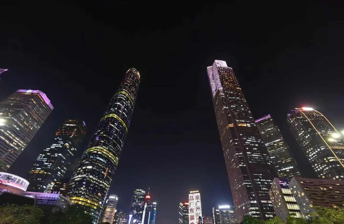 Nighttime city skyline with tall, illuminated skyscrapers against a dark sky, colorful building lights creating a vibrant urban vista