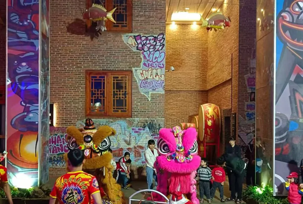 Leizhou Ancient City,Leizhou,Chinatour Two colorful lion dance costumes (pink and brown) performing in a brick-walled alley while children watch nearby.