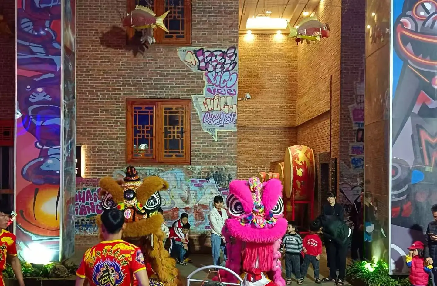 Leizhou Ancient City,Leizhou,Chinatour Two colorful lion dance costumes (pink and brown) performing in a brick-walled alley while children watch nearby.