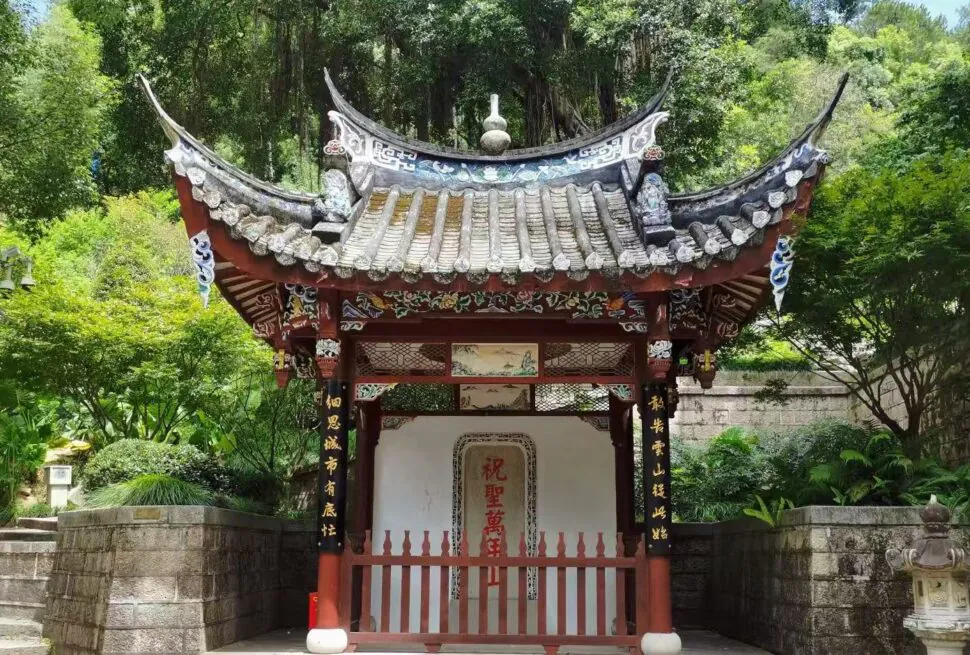 Drum Mountain Scenic Area,Fuzhou,Chinatour Traditional Chinese pavilion with a curved tiled roof and red wooden pillars set in a lush garden. (Informative, scene-setting)