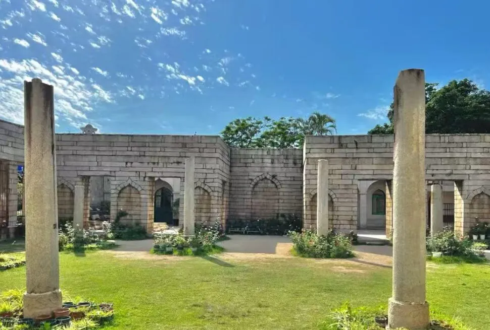 Qingjing Mosque,Quanzhou,Chinatour Stone-clad courtyard with arches and tall columns, green lawn, and a bright blue sky behind the historic structure.