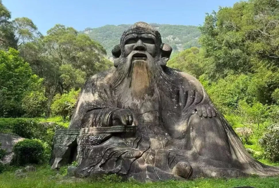 Mount Qingyuan Scenic Area,Quanzhou,Chinatour Large stone statue of a seated ancient sage with a long beard in a lush garden/park setting.