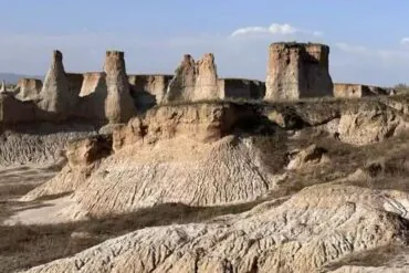 Earth Forest,Datong,Chinatour Desert badlands with tall eroded buttes and jagged ridges under a clear blue sky