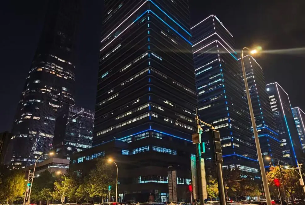 TEDA Modern Industrial Zone,Tianjin,Chinatour Night city street with sleek glass skyscrapers outlined in blue neon and traffic in the foreground.