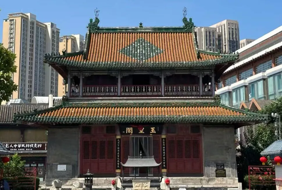 Tianhou Palace ,Tianjin,Chinatour Traditional Chinese temple with red doors and ornate green-tiled roof, set against modern high-rises in an urban plaza.