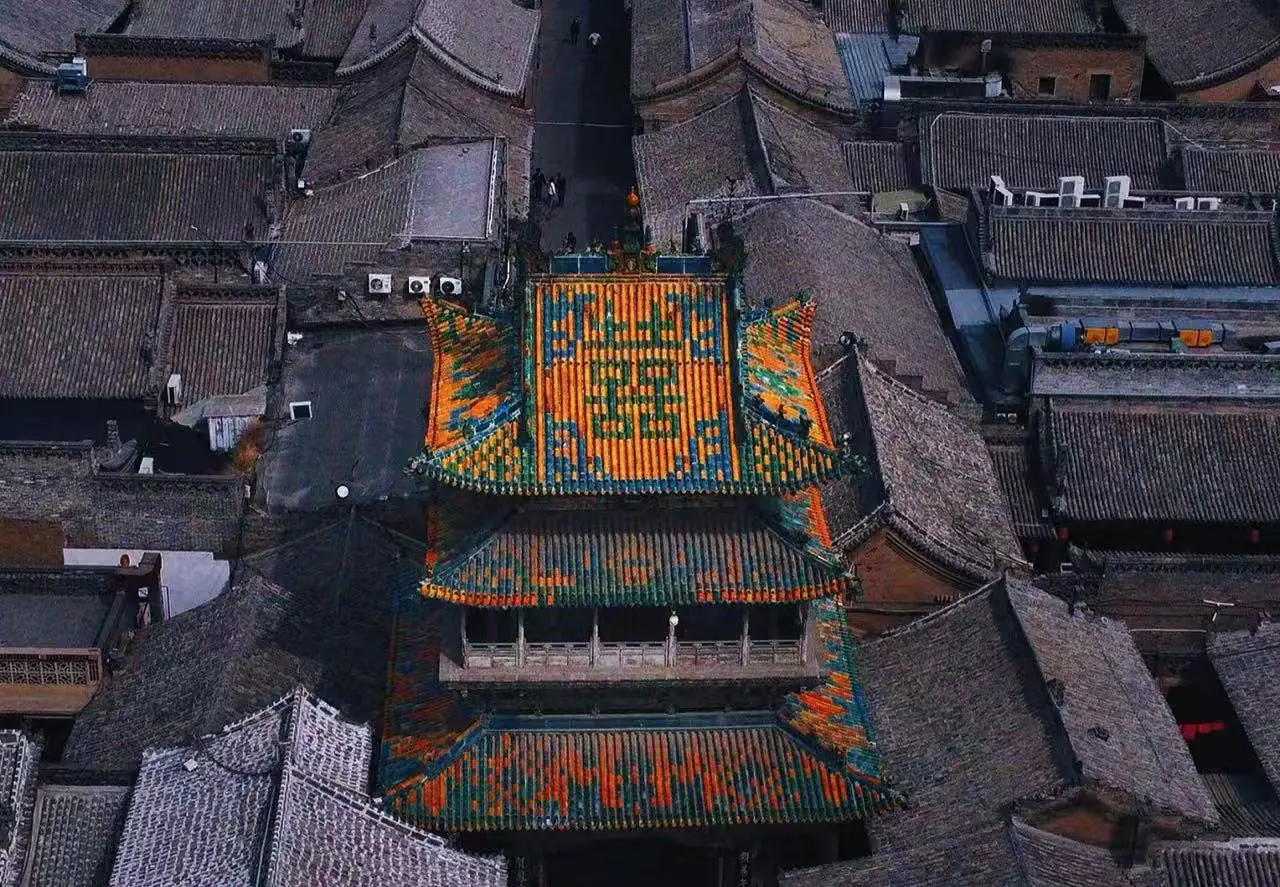 Qiao Family Courtyard,Pingyao,Chinatour Aerial view of a historic Chinese temple with a bright multicolored tiled roof surrounded by gray brick buildings