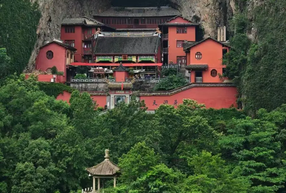 Yandang Mountain ,Wenzhou,Chinatour Red temple complex built into a rocky hillside, with traditional Chinese roofs amid green trees and garden walls