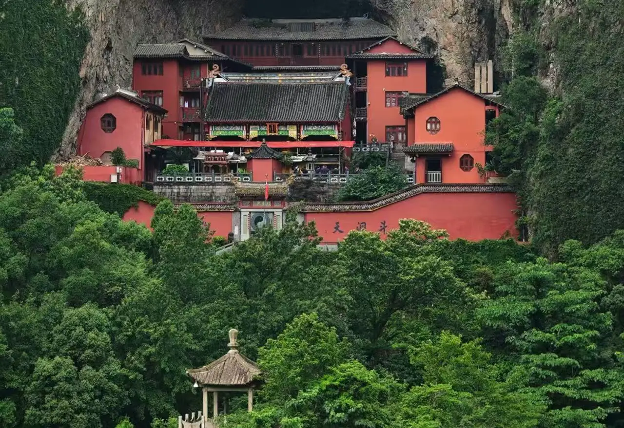 Yandang Mountain ,Wenzhou,Chinatour Red temple complex built into a rocky hillside, with traditional Chinese roofs amid green trees and garden walls