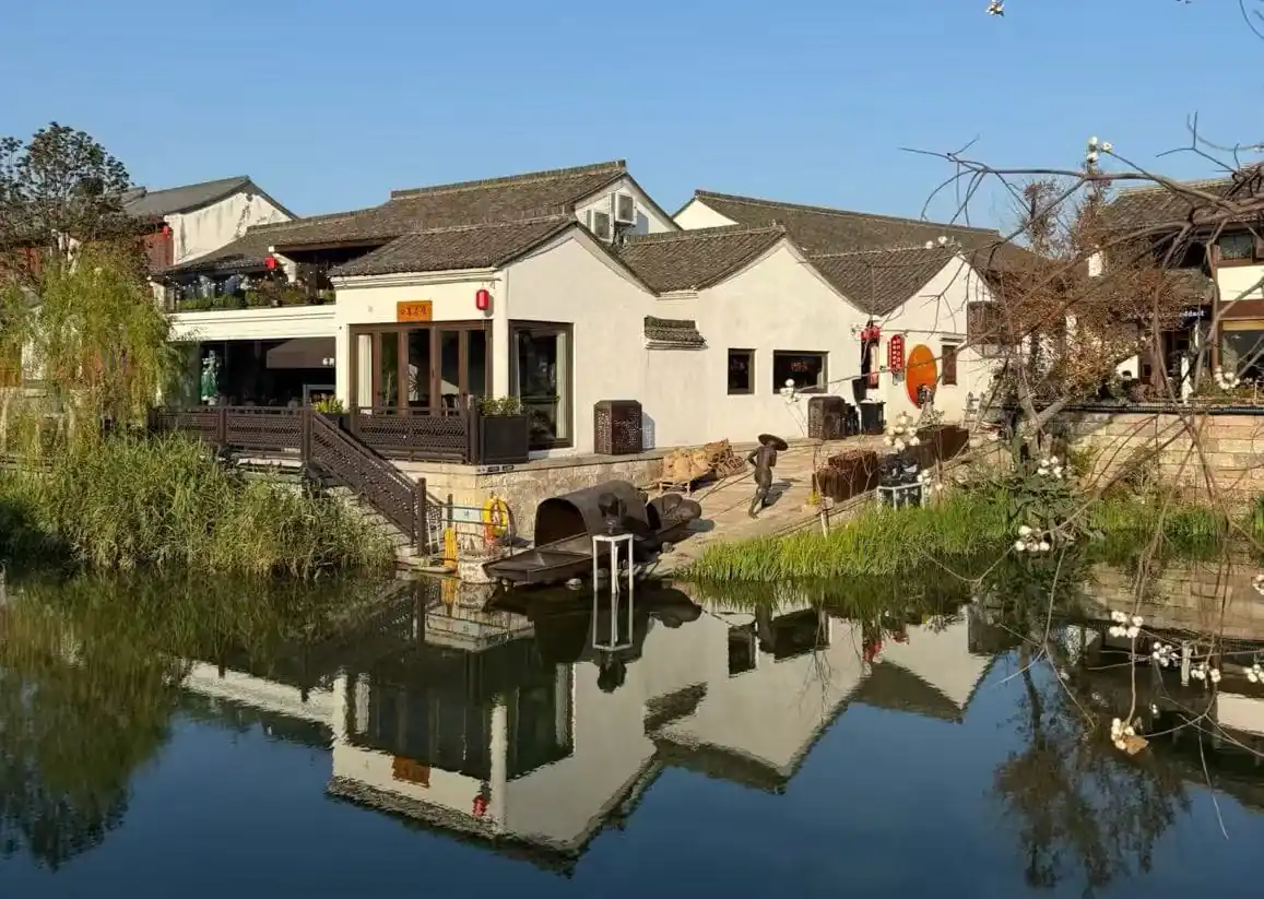 Cao'e River Pedestrian Street ,Shaoxing,Chinatour White-walled buildings with gray tiled roofs along a calm canal, their reflection rippling in the water.