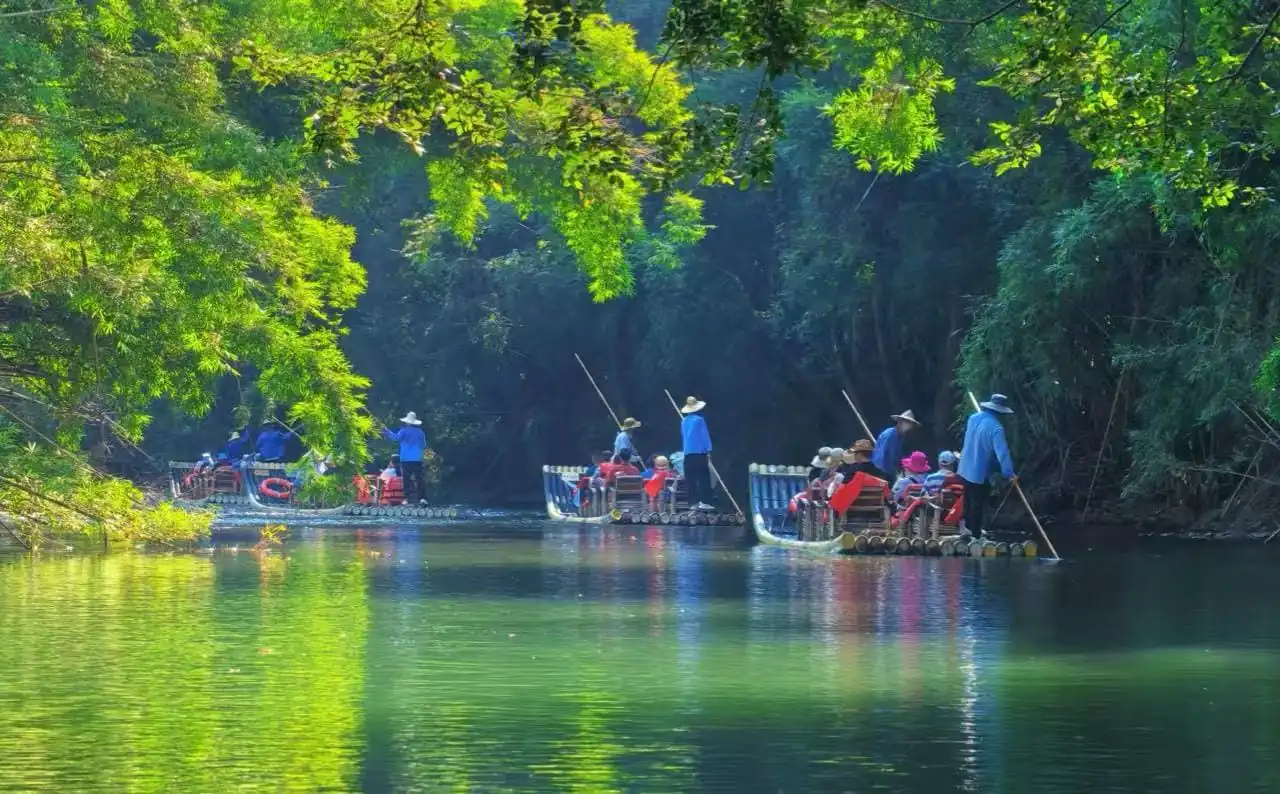 Nine-Bend Stream,Nanping,Chinatour Group of people in red life jackets ride bamboo rafts down a calm, green river guided by polesmen in blue shirts.