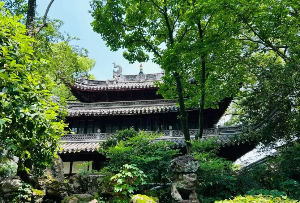 Tianyi Pavilion,Ningbo,Chinatour Traditional Chinese temple nestled in lush garden, with curved tiled roofs and stone dragon ornament at the ridge amid green trees