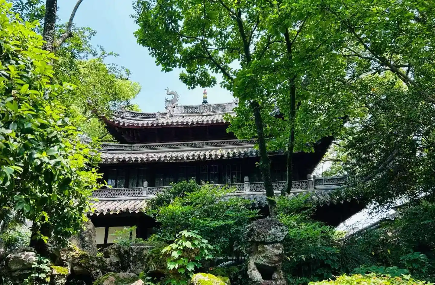 Tianyi Pavilion,Ningbo,Chinatour Traditional Chinese temple nestled in lush garden, with curved tiled roofs and stone dragon ornament at the ridge amid green trees