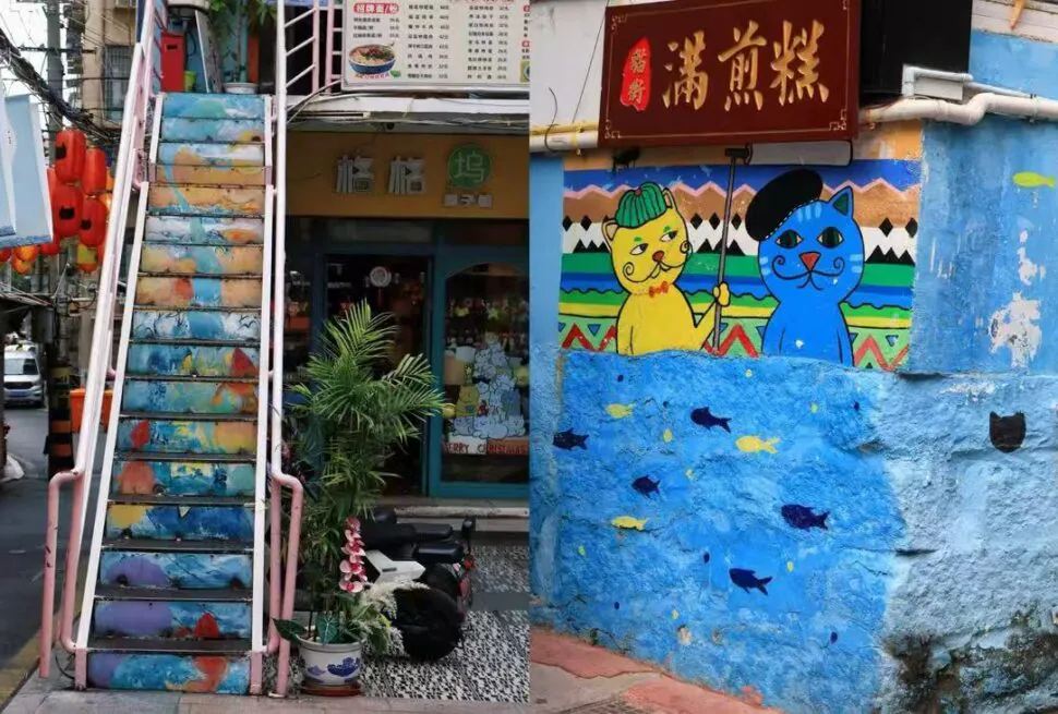 Colorful outdoor stairway beside a storefront, with a mural of two cats on a bright blue wall and a red sign above.