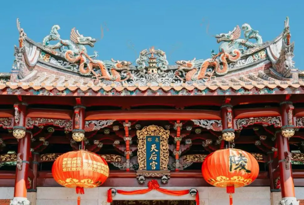 Tianhou Temple,Quanzhou,Chinatour Entrance of a traditional Chinese temple with an ornate dragon-adorned roof, red columns, and two red lanterns; plaque reads 天后宮.