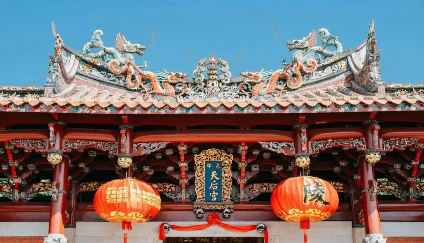 Tianhou Temple,Quanzhou,Chinatour Entrance of a traditional Chinese temple with an ornate dragon-adorned roof, red columns, and two red lanterns; plaque reads 天后宮.