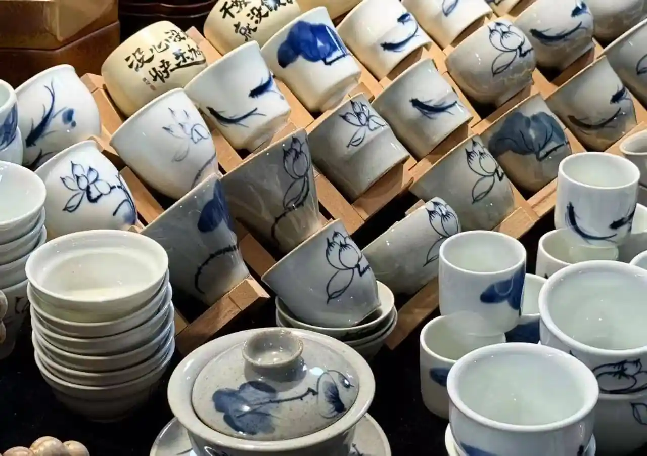 Stacks and rows of white ceramic bowls and cups with blue floral designs for sale or display.