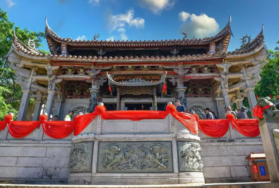 Ornate Chinese temple with carved stone railing, red fabric decor, and visitors on a sunny day.Meizhou Island Mazu Temple,Putian,Fujian,Chinatravel