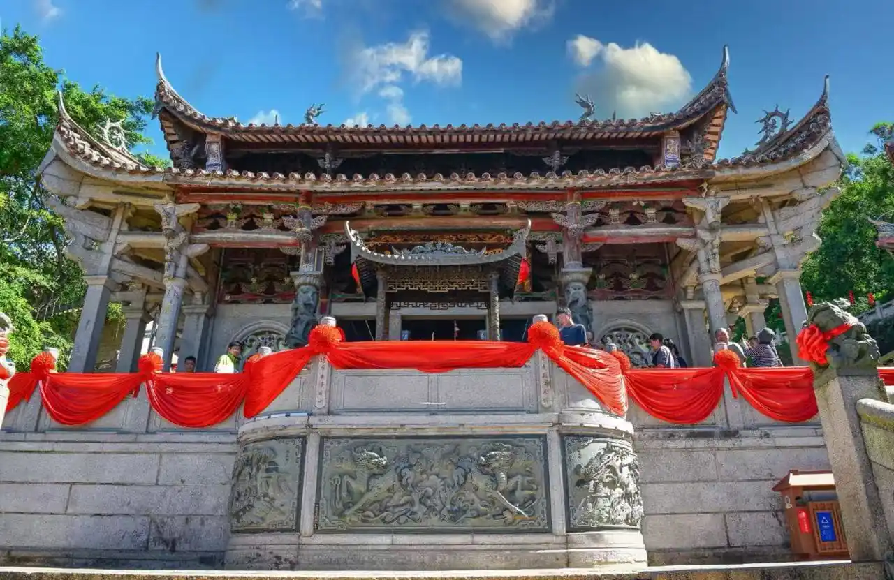 Ornate Chinese temple with carved stone railing, red fabric decor, and visitors on a sunny day.Meizhou Island Mazu Temple,Putian,Fujian,Chinatravel