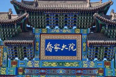 Ornate Chinese temple gate with multicolored carvings and a blue plaque with white Chinese characters