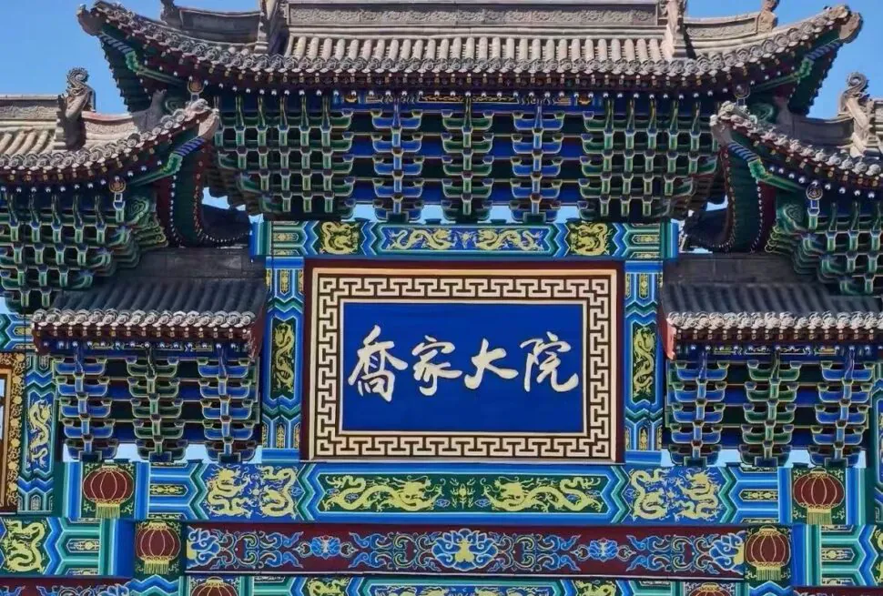 Qiao Family Courtyard,Pingyao,Chinatour Ornate Chinese temple gate with multicolored carvings and a blue plaque with white Chinese characters