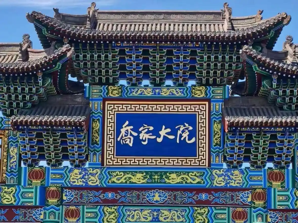 Qiao Family Courtyard,Pingyao,Chinatour Ornate Chinese temple gate with multicolored carvings and a blue plaque with white Chinese characters
