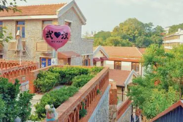 A pink heart-shaped balloon reading 'WU HAN' floats above a brick courtyard in a charming village with tiled roofs and greenery.Tanhualin Old Street,Wuhan,Hubei ,Chinatravel