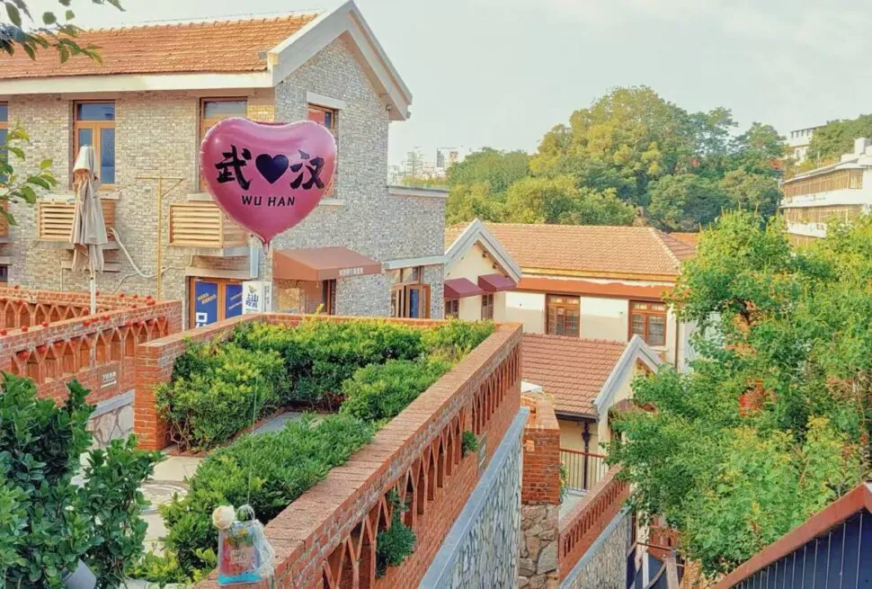 A pink heart-shaped balloon reading 'WU HAN' floats above a brick courtyard in a charming village with tiled roofs and greenery.Tanhualin Old Street,Wuhan,Hubei ,Chinatravel
