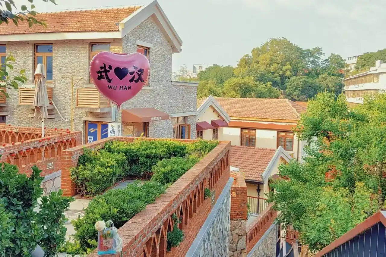 A pink heart-shaped balloon reading 'WU HAN' floats above a brick courtyard in a charming village with tiled roofs and greenery.Tanhualin Old Street,Wuhan,Hubei ,Chinatravel