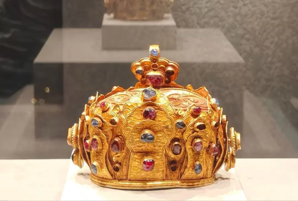 Ornate gold crown encrusted with red and blue gems on display in a glass case.Yunnan Provincial Museum,Kunming,Yunnan ,Chinatravel