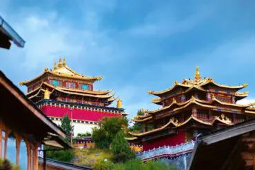 Traditional temple complex with gold-topped pagodas and red walls under a blue sky.Dukezong Ancient Town,Shangri-La,Yunnan,Chinatravel