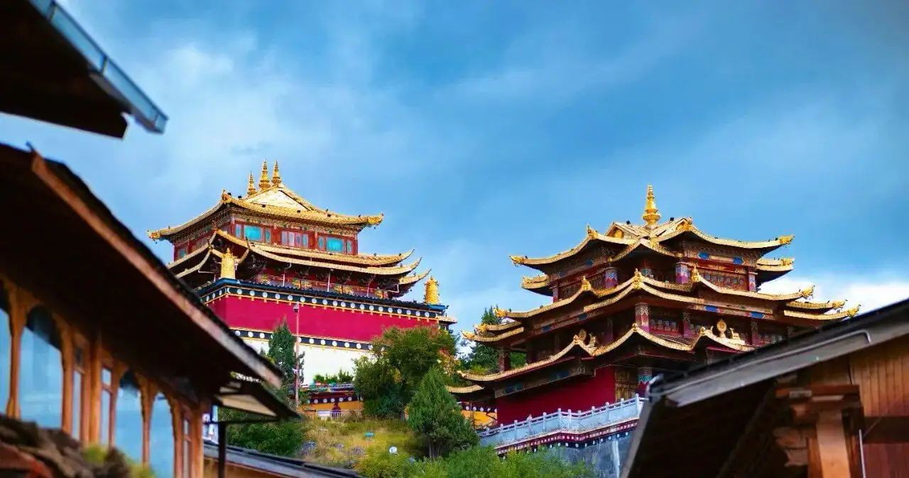 Traditional temple complex with gold-topped pagodas and red walls under a blue sky.Dukezong Ancient Town,Shangri-La,Yunnan,Chinatravel