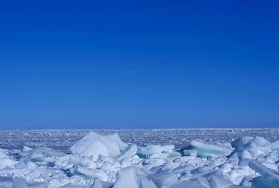 Ice-covered shore with jagged white ice chunks under a clear blue sky, Arctic horizon in the distance.Qinghai Lake,Xining,Qinghai