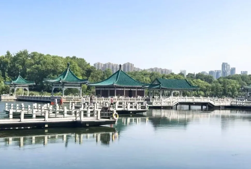 Green-roofed pavilions on a calm lake, connected by white bridges, with trees and a distant city skyline.East Lake Scenic Area,Wuhan,Hubei ,Chinatravel