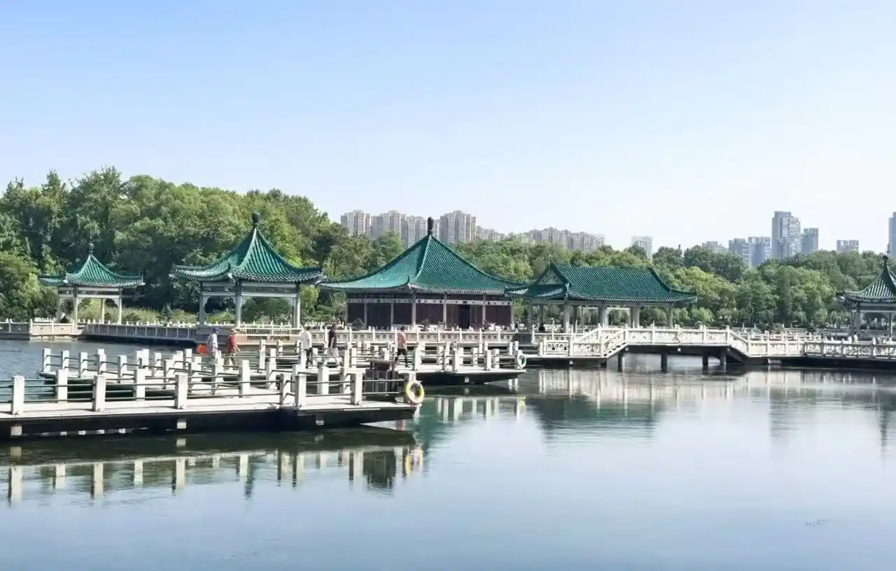 Green-roofed pavilions on a calm lake, connected by white bridges, with trees and a distant city skyline.East Lake Scenic Area,Wuhan,Hubei ,Chinatravel