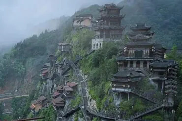 Series of traditional Chinese pagoda-style temples perched on a misty mountainside along a steep cliff.Wangxian Valley,Shangrao,Jiangxi,Chinatravel