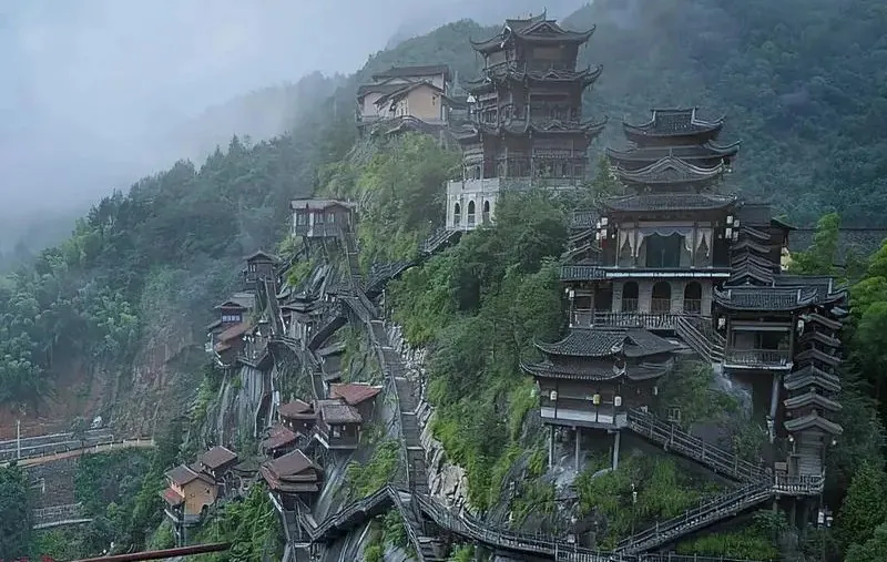 Series of traditional Chinese pagoda-style temples perched on a misty mountainside along a steep cliff.Wangxian Valley,Shangrao,Jiangxi,Chinatravel