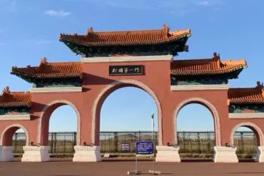 Manzhouli Border Gate,Hulunbuir,Chinatour Traditional Chinese gate with three arches, red walls, and ornate teal-tiled roofs under a blue sky.