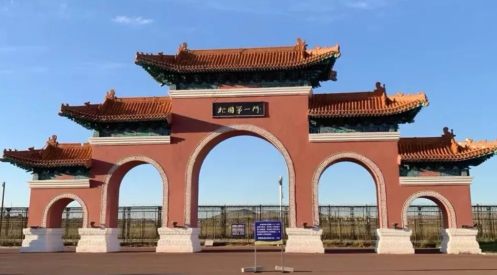 Manzhouli Border Gate,Hulunbuir,Chinatour Traditional Chinese gate with three arches, red walls, and ornate teal-tiled roofs under a blue sky.