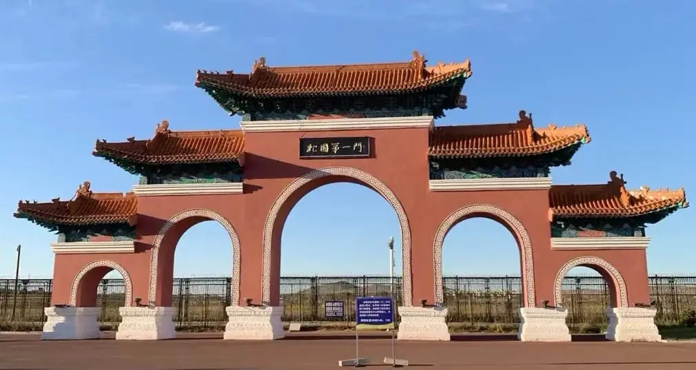 Manzhouli Border Gate,Hulunbuir,Chinatour Traditional Chinese gate with three arches, red walls, and ornate teal-tiled roofs under a blue sky.