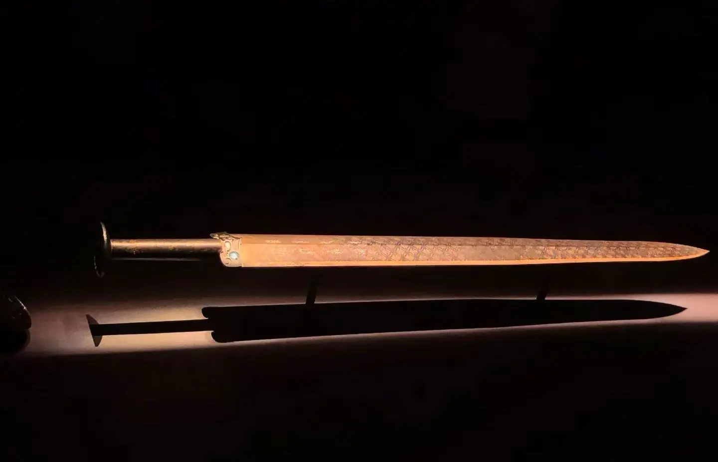 Ornate dagger with a metal hilt and long slim blade, placed above a brown sheath on a dark surface.Hubei Provincial Museum,Wuhan,Hubei ,Chinatravel