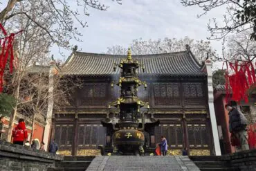 Traditional Chinese temple with a tall tiered incense burner in front and red ribbons hanging from trees in the courtyard.Changchun Guan Taoist Temple,Wuhan,Hubei ,Chinatravel