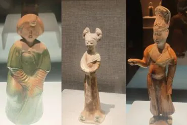 Henan Museum,Luoyang,Chinatour Triptych of ceramic figurines on display: a left green-gowned figure, a middle slim figure with two buns, and a right orange-robed figure with a raised arm.