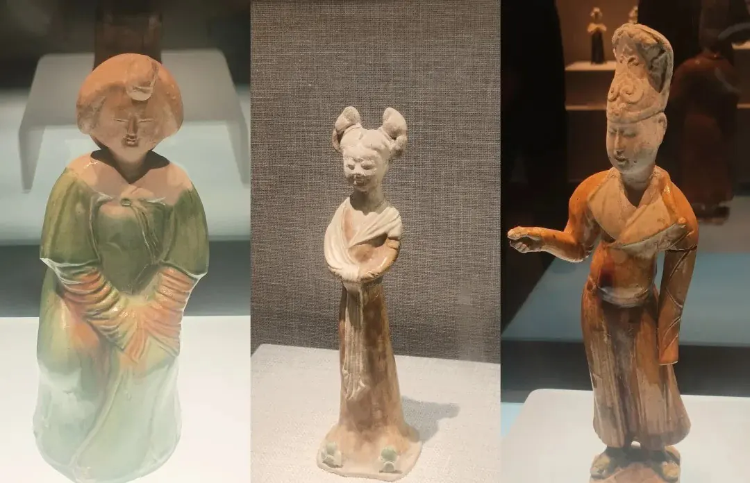Henan Museum,Luoyang,Chinatour Triptych of ceramic figurines on display: a left green-gowned figure, a middle slim figure with two buns, and a right orange-robed figure with a raised arm.