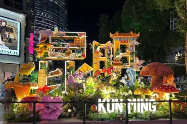 Night view of a vibrant illuminated garden sculpture display spelling 'Kunming' with flowers, mushrooms, and Chinese architectural elements in a city plaza at night.Nanping Commercial Street,Kunming,Yunnan ,Chinatravel
